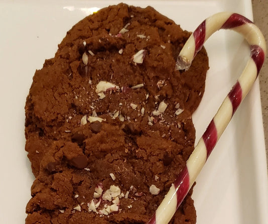 Chocolate cookies with a candy cane on a white plate.