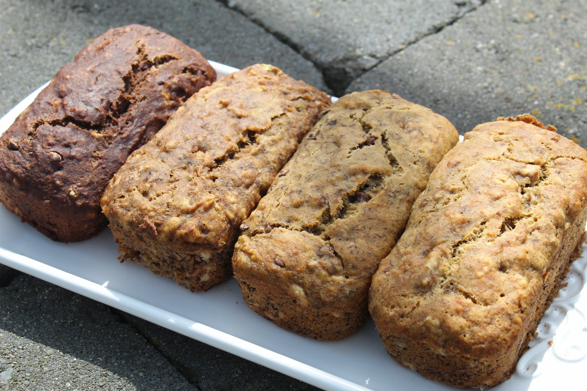 Four loaves of bread on a white plate with a concrete floor background