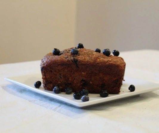 Min Loaf of bread with blueberries on a white plate.
