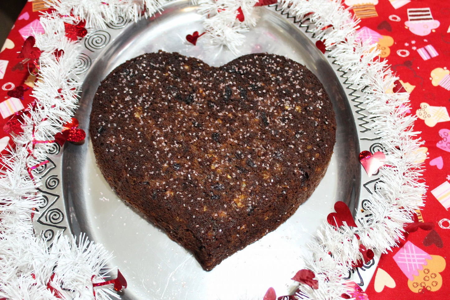 Double chocolate cherry bundt cake in a heart shape with sprinkles.