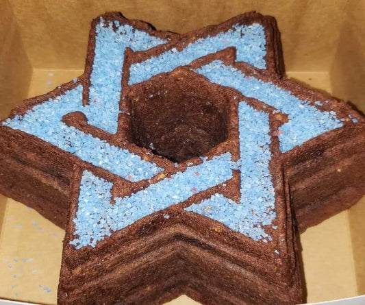 A Jewish Star–shaped Bundt cake topped with chocolate and blue sprinkles inside a box.