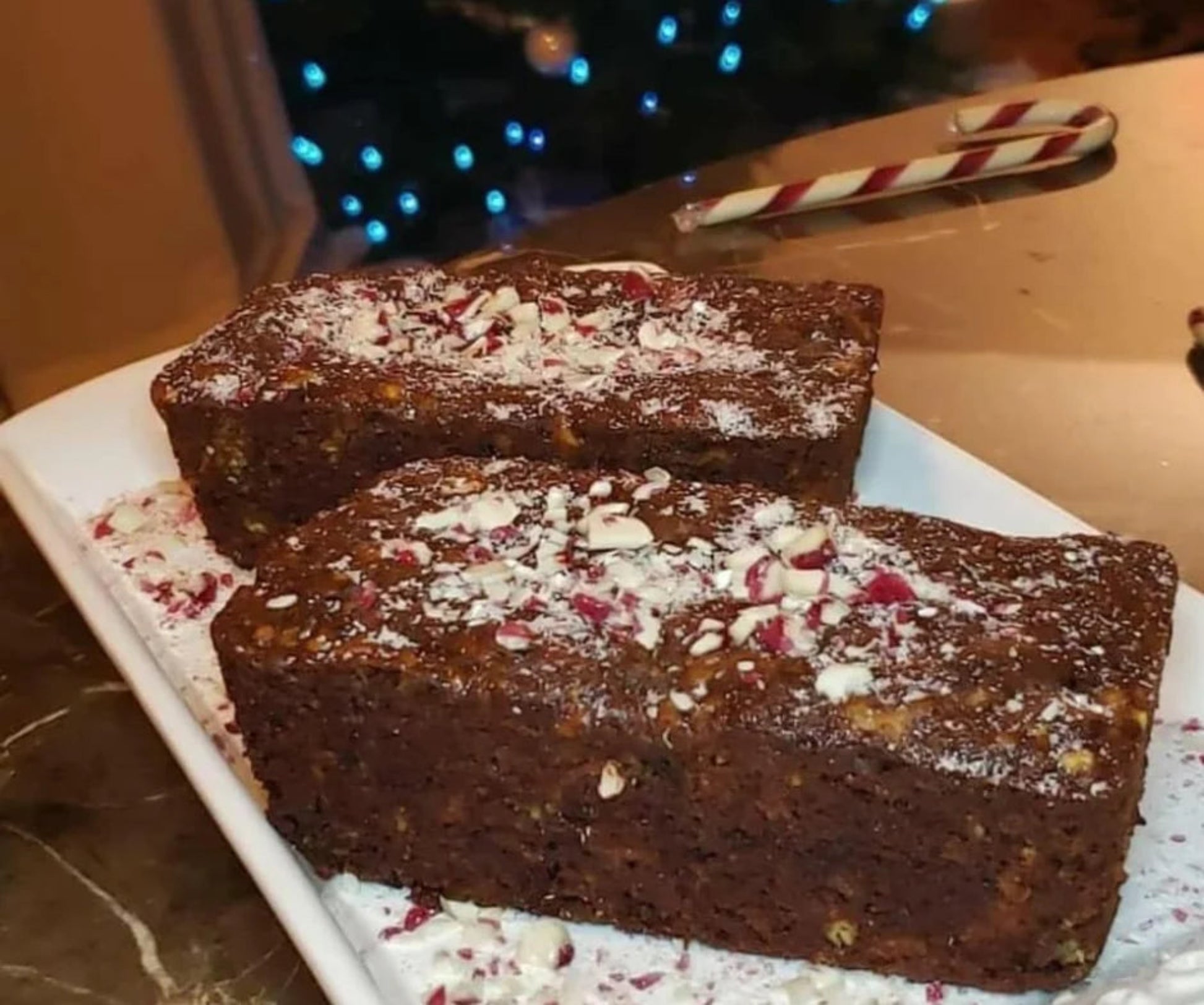 Two mini loaves lots of peppermint on a white plate, with a festive background.