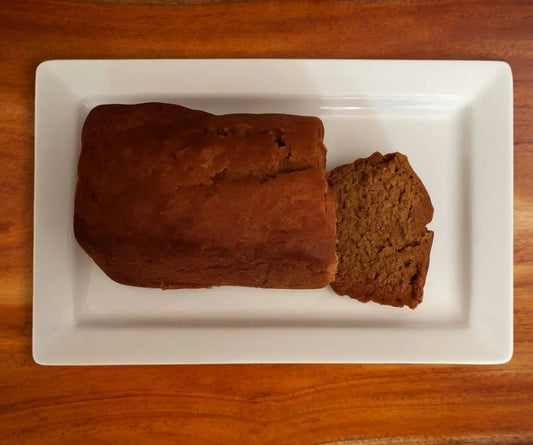 Loaf of pumpkin bread with a slice cut off on a white plate.