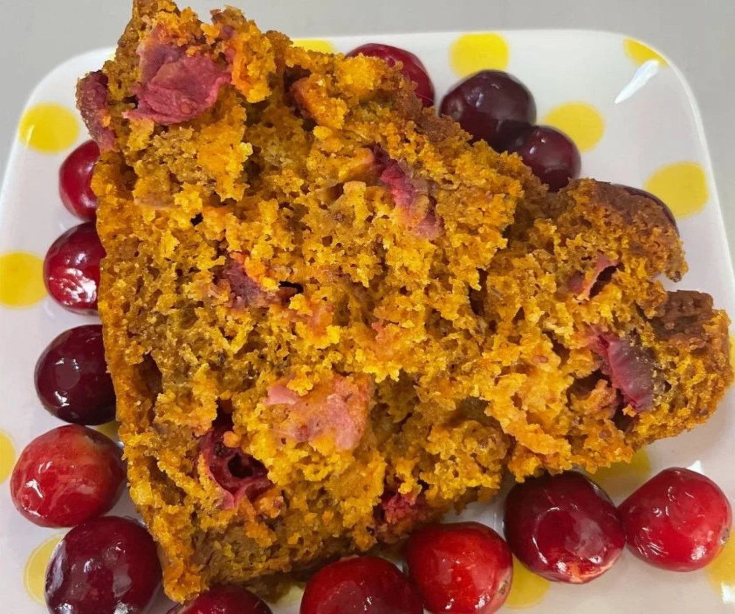 Sliced pumpkin bread with cranberries on a plate.